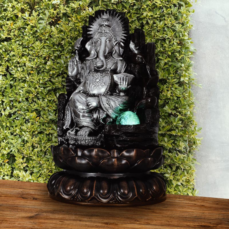 "Ezüst színű Ganesha szobai csobogó - egy elegáns, ezüst színű Ganesh szoborral díszített asztali vízjáték, amely szellemi béke és jó szerencse szimbólumaként szolgál."