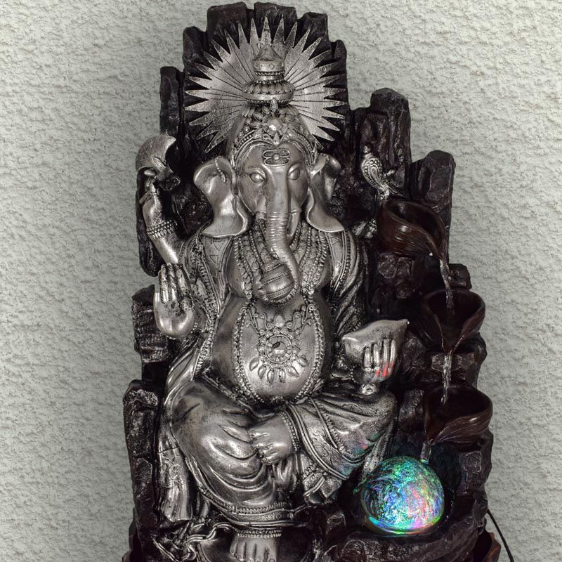 "Ezüst színű Ganesha szobai csobogó - egy elegáns, ezüst színű Ganesh szoborral díszített asztali vízjáték, amely szellemi béke és jó szerencse szimbólumaként szolgál."