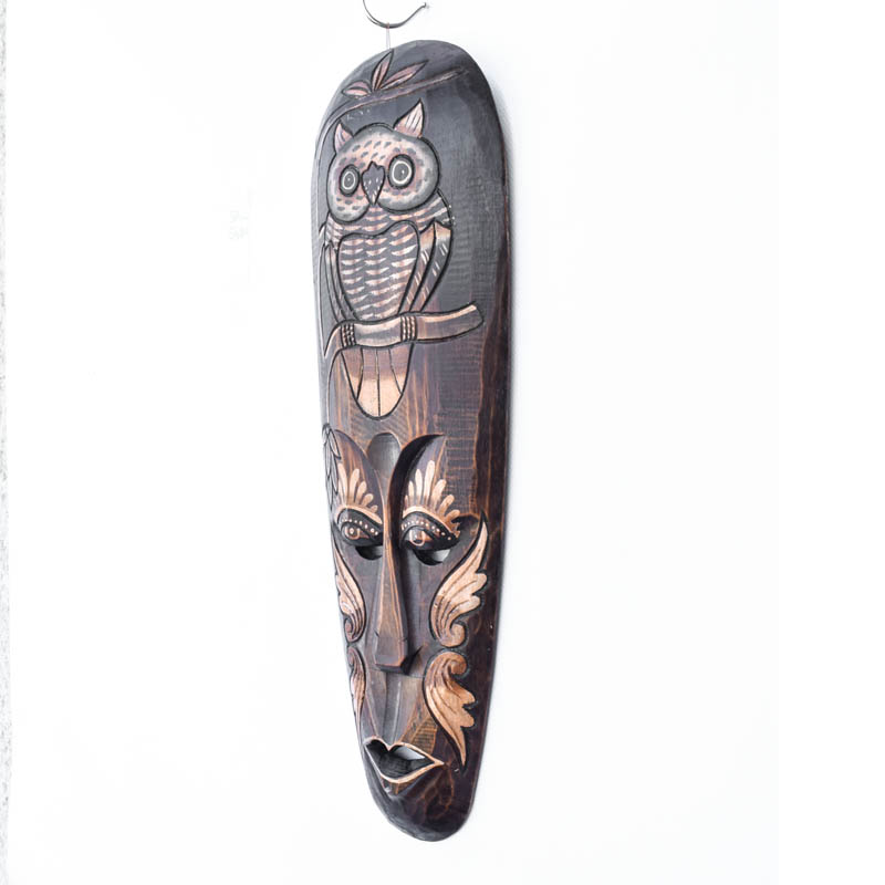 Indonéz fa maszk, bagoly szimbólummal: Egy gyönyörűen faragott fa maszk, amelyen a bagoly szimbóluma díszíti a felületét